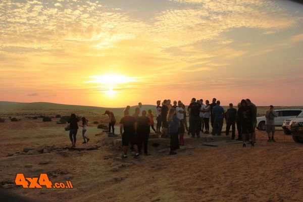 שיחת סיכום בבור המים באמצע השטח על רקע השקיעה 
